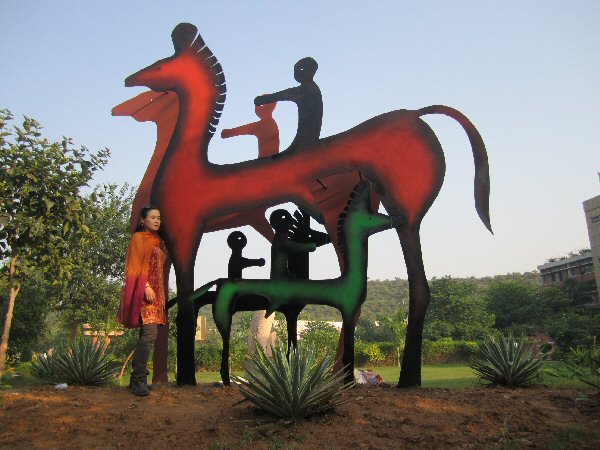 Sculptor Zhang Yaxi next to her completed equestrian sculpture installation in painted steel